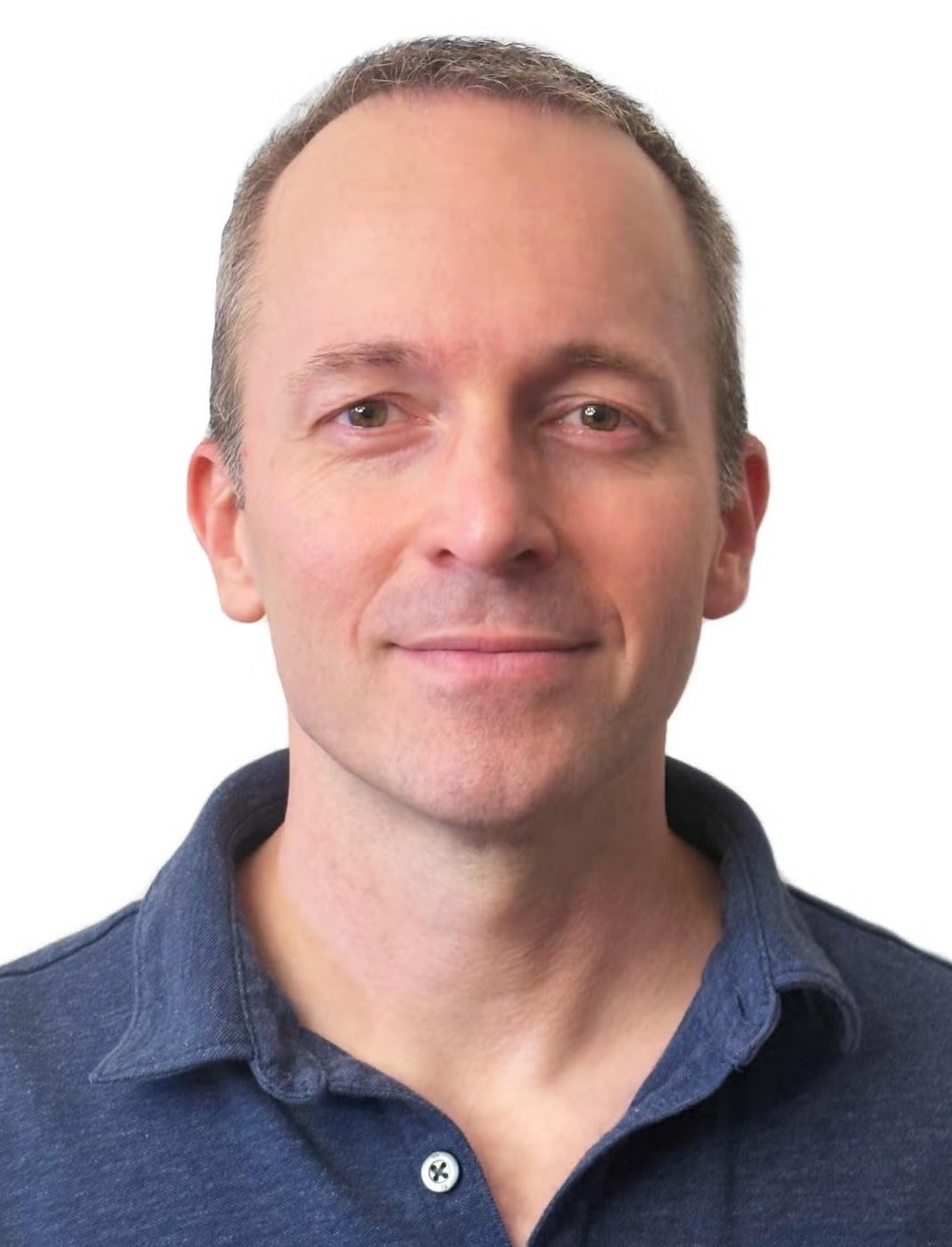 A man in a collared shirt with short hair smiles